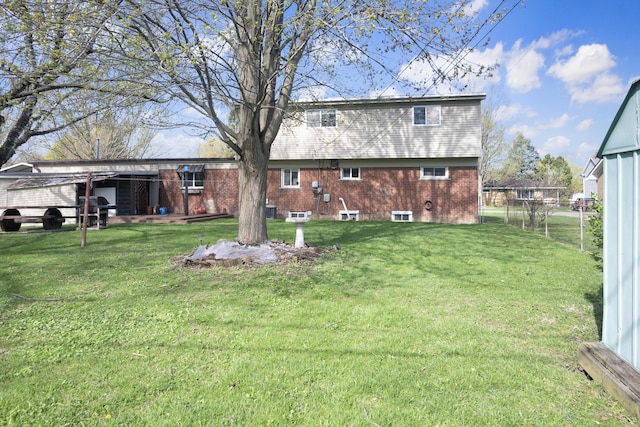 rear view of property featuring fence, a yard, and brick siding