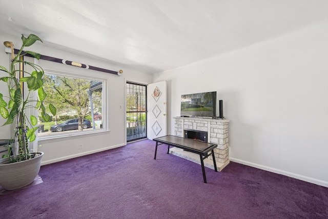 carpeted living area with a warm lit fireplace and baseboards