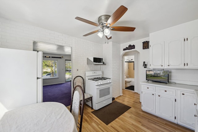 kitchen with white appliances, light wood-type flooring, arched walkways, white cabinets, and a ceiling fan