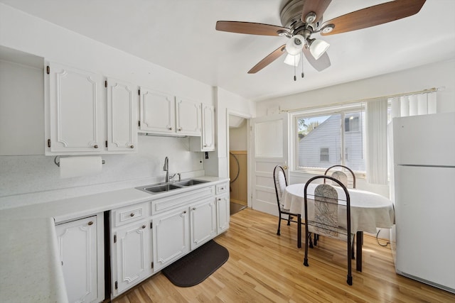 kitchen with freestanding refrigerator, white cabinets, ceiling fan, and a sink