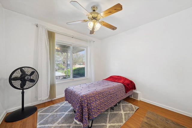 bedroom with baseboards, a ceiling fan, wood finished floors, and visible vents