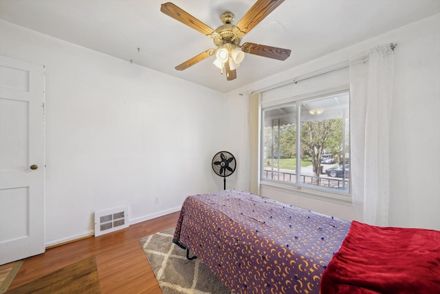 bedroom featuring visible vents, baseboards, ceiling fan, and wood finished floors
