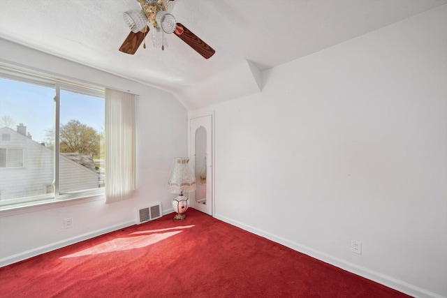 carpeted spare room featuring vaulted ceiling, baseboards, a ceiling fan, and visible vents