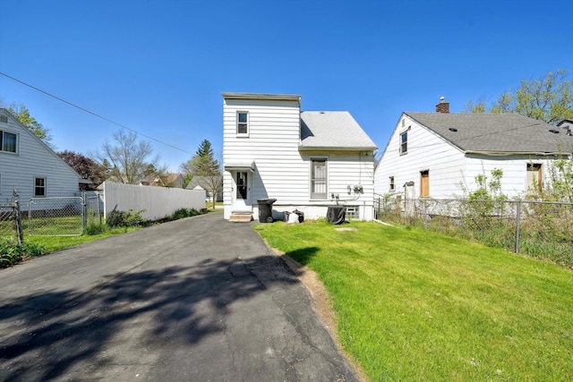 back of house featuring fence, a yard, and roof with shingles