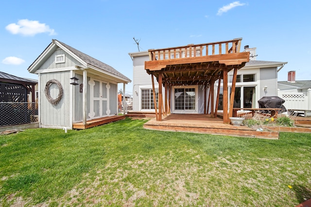 back of property with a shed, an outdoor structure, a lawn, and a deck