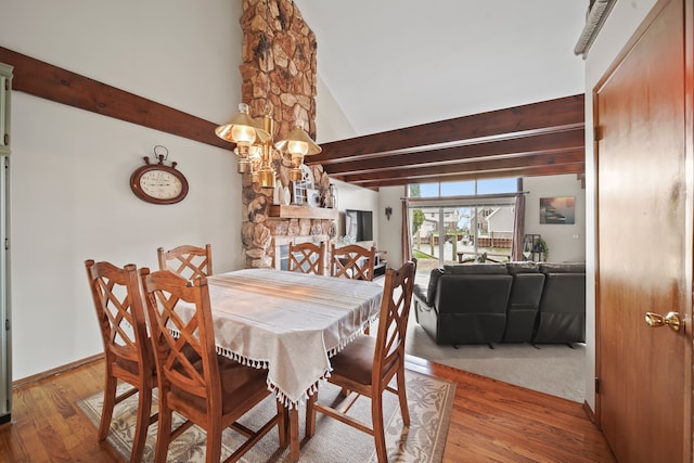 dining room with an inviting chandelier, high vaulted ceiling, beamed ceiling, and wood finished floors