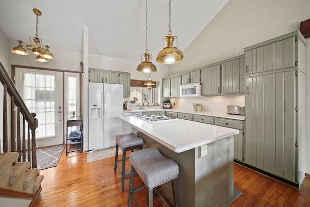kitchen featuring light countertops, high vaulted ceiling, white appliances, and a healthy amount of sunlight