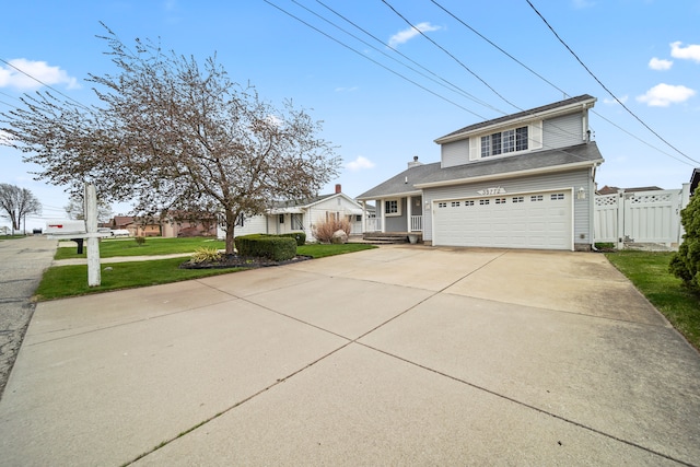 traditional-style house with concrete driveway, an attached garage, fence, and a front lawn