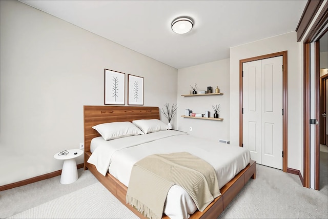bedroom with a closet, baseboards, and light carpet