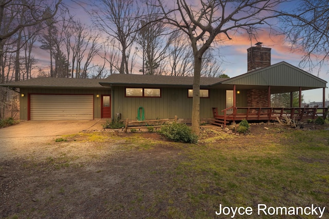 view of front of property featuring a lawn, driveway, an attached garage, and a chimney