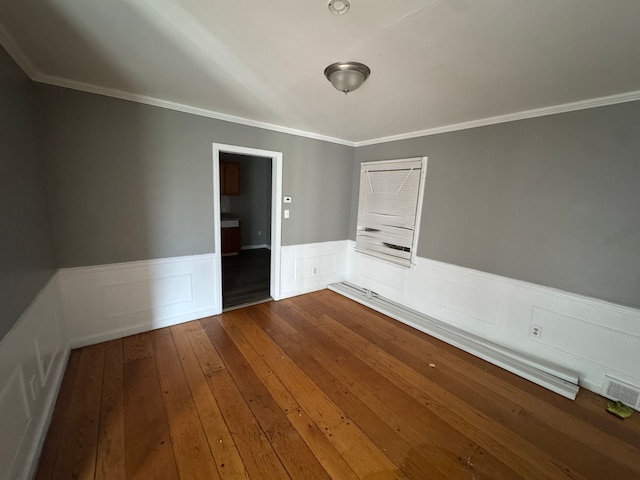 empty room with dark wood-style flooring, visible vents, ornamental molding, and wainscoting