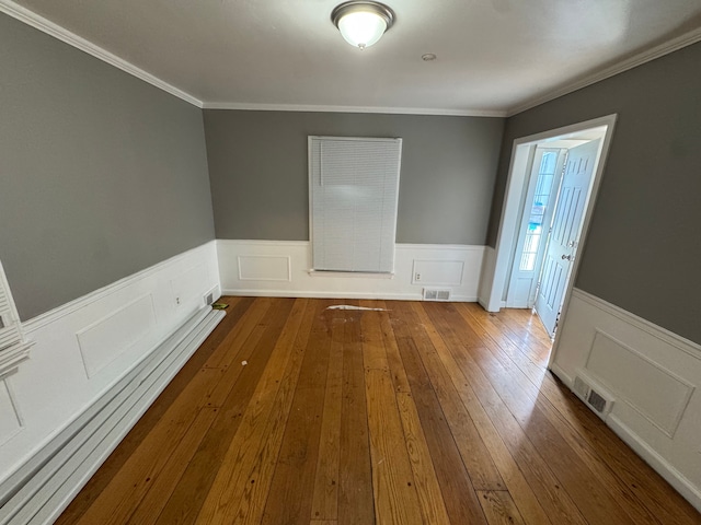 unfurnished room featuring ornamental molding, visible vents, and wainscoting