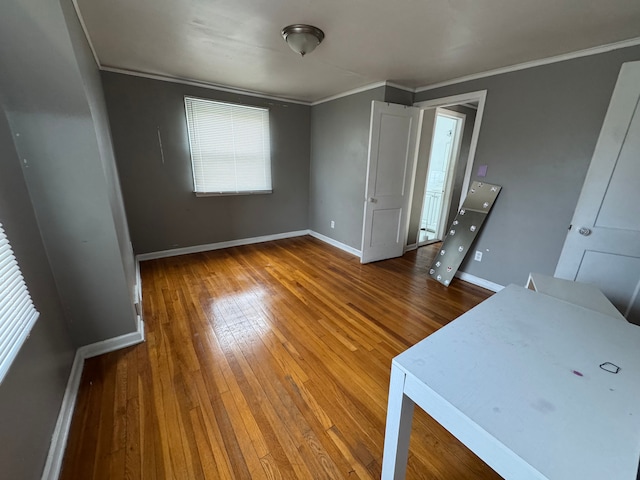 unfurnished bedroom with ornamental molding, hardwood / wood-style flooring, and baseboards