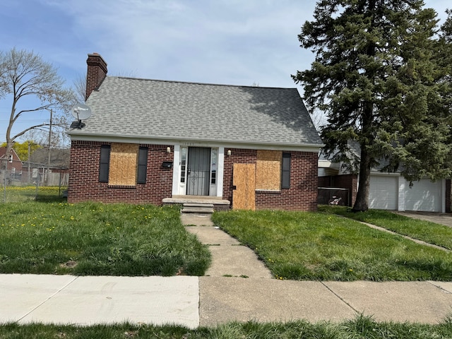 view of front of house featuring a front lawn, a chimney, a shingled roof, and brick siding
