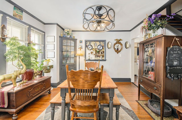dining area featuring light wood-type flooring, ornamental molding, baseboards, and a notable chandelier