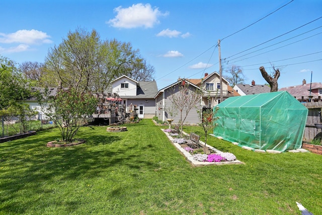 view of yard with an outdoor structure, fence, and a greenhouse