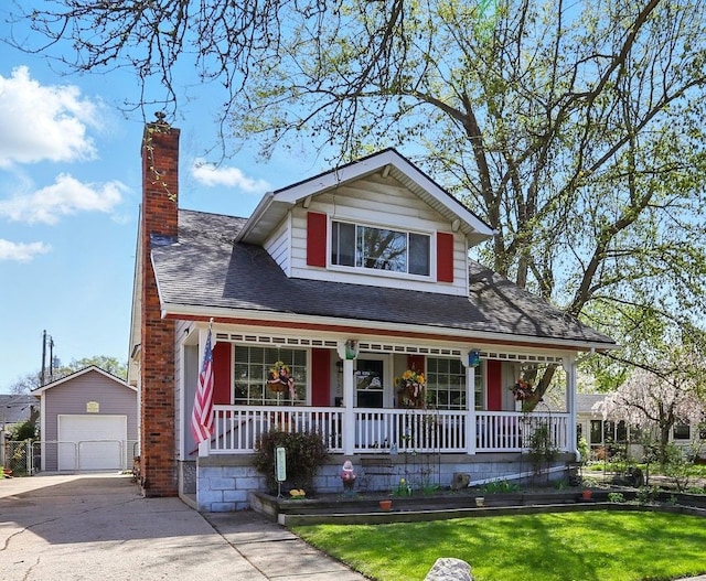 view of front of home with a porch, a chimney, a garage, an outdoor structure, and concrete driveway