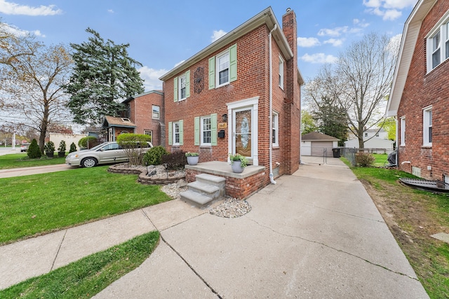 view of front of home featuring an outdoor structure, brick siding, a front lawn, and a chimney