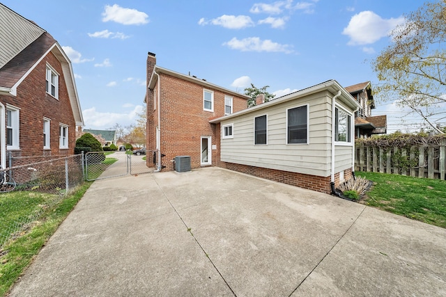 rear view of house featuring a gate, fence, a patio, and central air condition unit