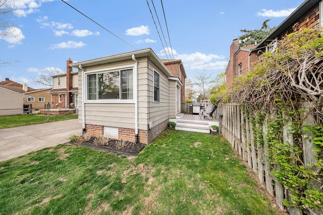 view of side of home with a lawn, a deck, and fence