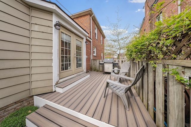 wooden deck with a grill, fence, and french doors