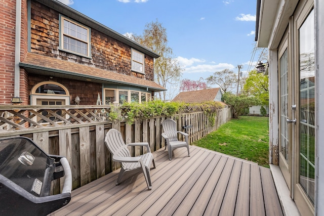 wooden terrace featuring fence, grilling area, and a yard