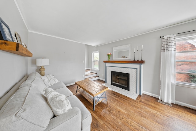 living room featuring a tile fireplace, visible vents, wood finished floors, and baseboards