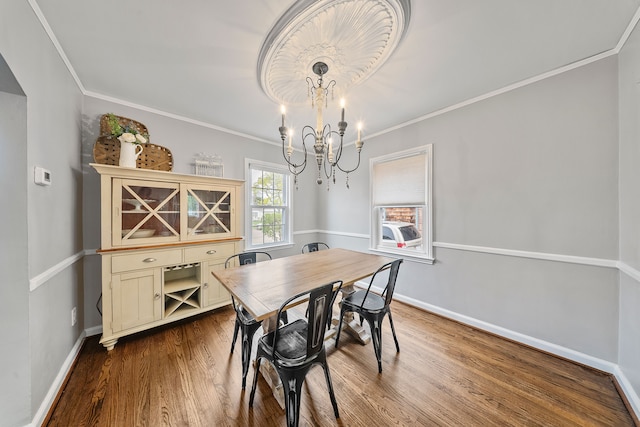 dining area featuring a chandelier, baseboards, crown molding, and dark wood finished floors