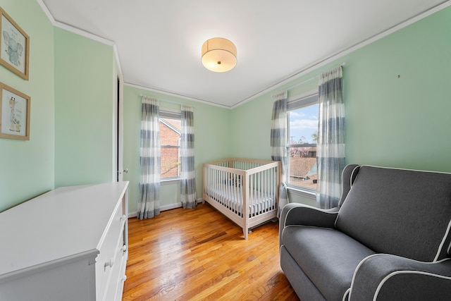 bedroom with ornamental molding, baseboards, and light wood-type flooring