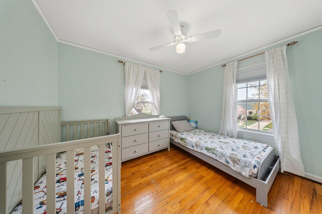 bedroom featuring ceiling fan, light wood-type flooring, and ornamental molding