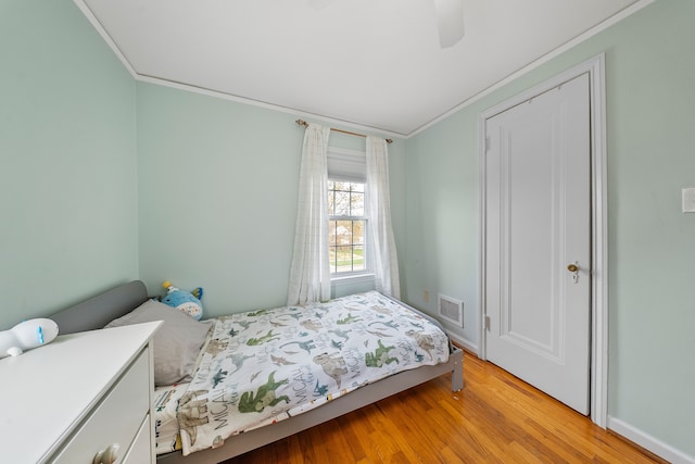 bedroom featuring crown molding, visible vents, ceiling fan, light wood-style floors, and baseboards