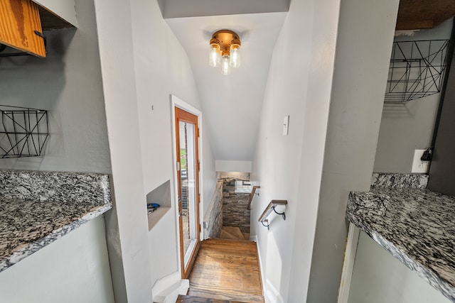 corridor with vaulted ceiling and light wood-style floors