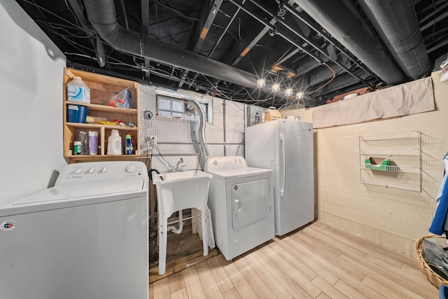 washroom featuring independent washer and dryer, light wood-type flooring, and laundry area