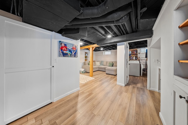 basement featuring light wood-style flooring, washer / dryer, and baseboards
