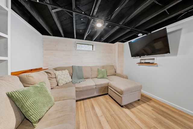 living area with baseboards, wood finished floors, and wooden walls