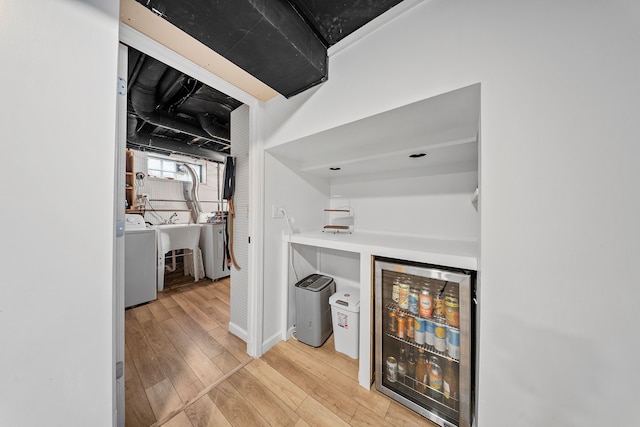 bar featuring beverage cooler, a dry bar, wood finished floors, and washer / clothes dryer