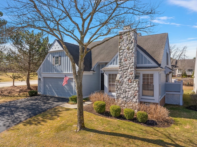 view of front of property featuring a chimney, a shingled roof, aphalt driveway, and a front yard