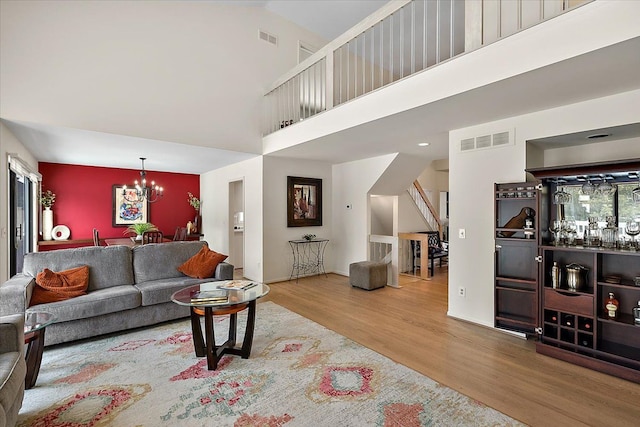 living room with stairway, a towering ceiling, wood finished floors, and visible vents
