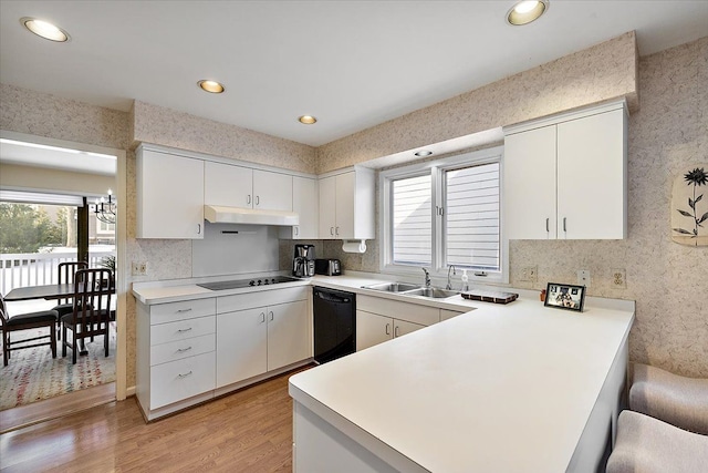 kitchen with a peninsula, a healthy amount of sunlight, a sink, and black appliances