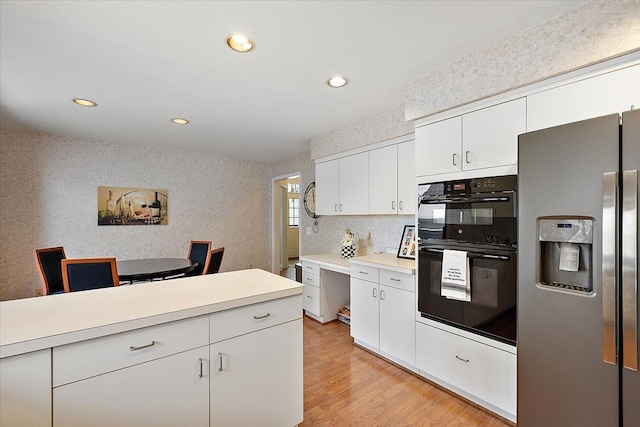 kitchen featuring light wood-style floors, dobule oven black, light countertops, stainless steel fridge, and recessed lighting