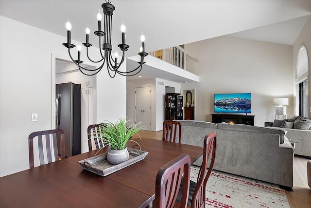 dining room with a high ceiling, an inviting chandelier, visible vents, and light wood-type flooring