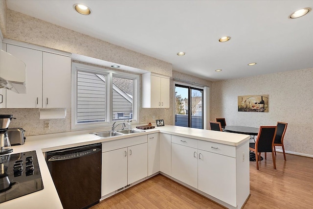 kitchen featuring a sink, light wood-type flooring, black appliances, and a peninsula