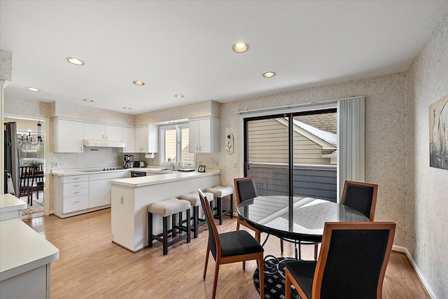 dining area featuring recessed lighting, light wood-style flooring, a notable chandelier, and wallpapered walls