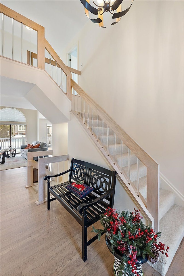 stairs with a high ceiling, a chandelier, and wood finished floors