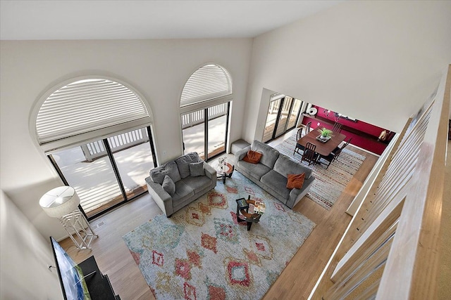 living area with visible vents, wood finished floors, and high vaulted ceiling