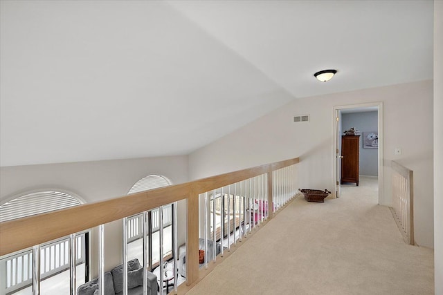 hall with visible vents, carpet floors, and lofted ceiling
