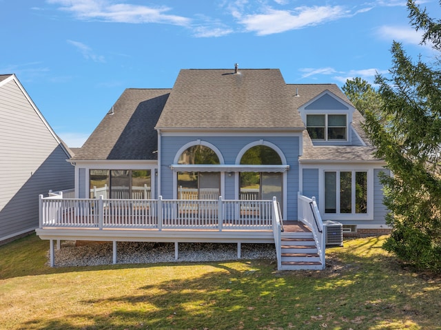 rear view of house with a shingled roof, a wooden deck, and a yard