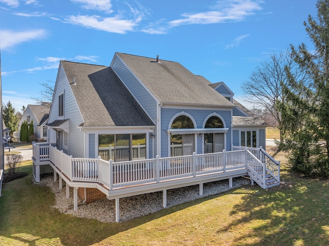 rear view of property with a lawn, roof with shingles, and a deck
