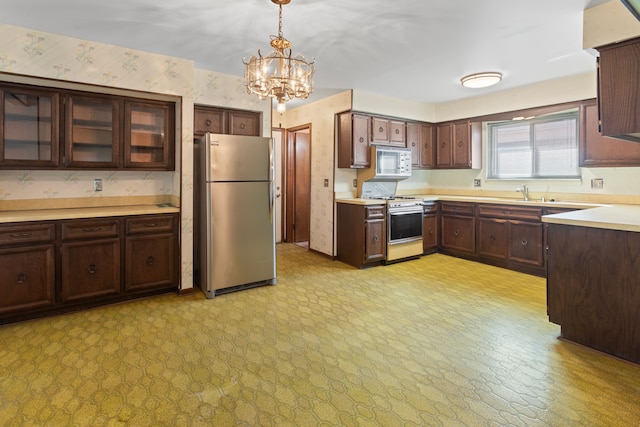 15895 Bexley St, Clinton Township, MI 48038 - kitchen featuring an inviting chandelier, white appliances, dark brown cabinetry, light countertops, and wallpapered walls