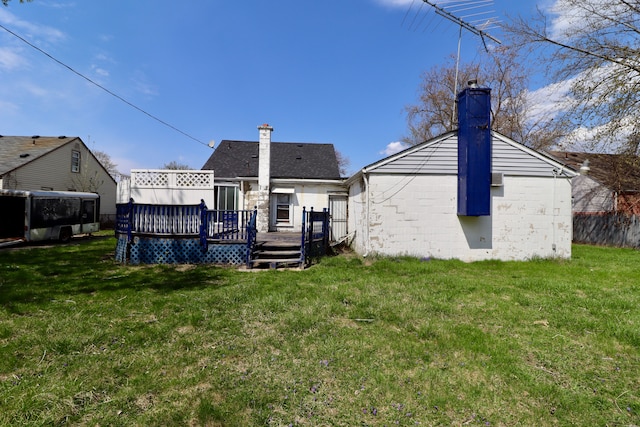 back of house featuring a wooden deck, a yard, and a chimney